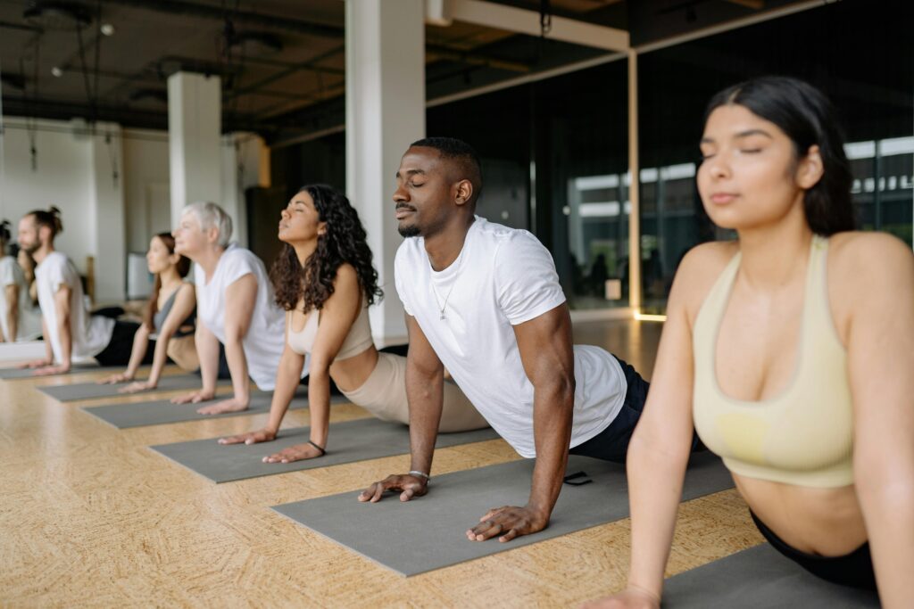 Group of people doing yoga stretch exercise in a modern fitness studio